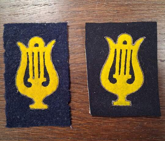 Yellow cutout lyre shapes, outlined in gold, set against a bluish iron-grey or black background. Very limited stock.
