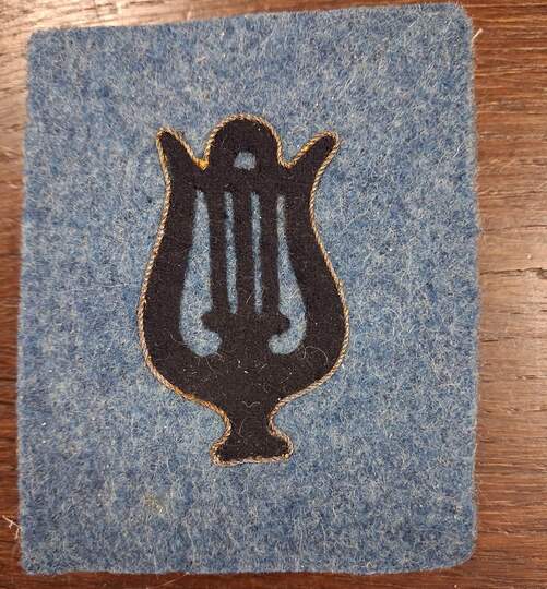 Blue cutout lyre shapes, outlined in gold, set against a horizon blue background. Very limited stock.