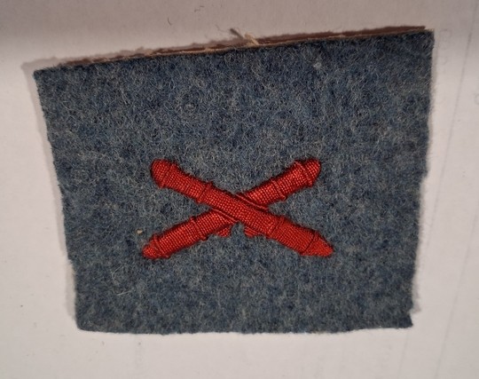WWI machine-gunner's badge, red silk on horizon-blue background, new old stock.